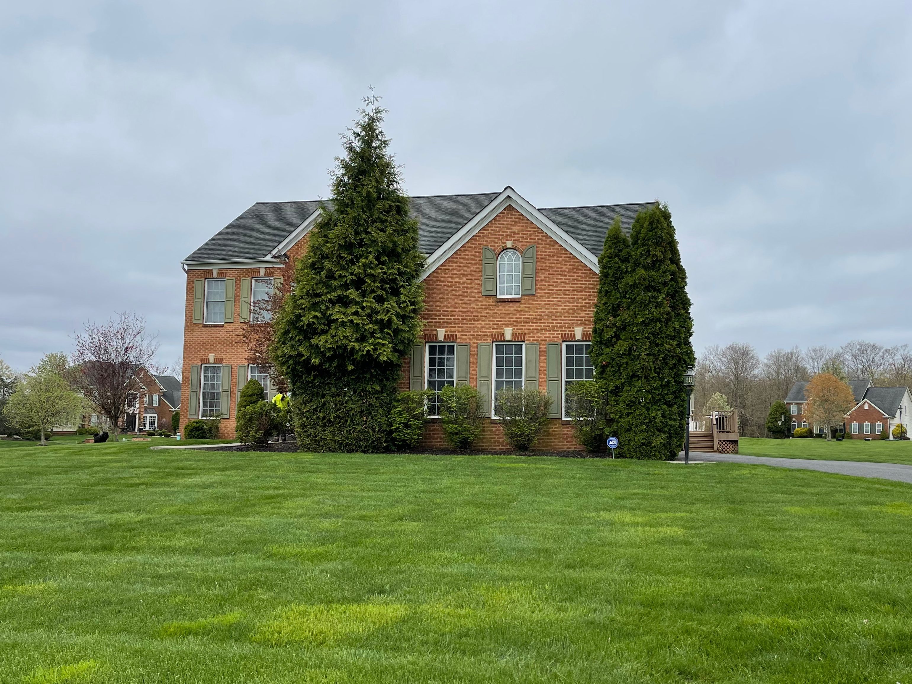 both photos are of the same red brick house. In the first photo there are 2 large trees that have been removed in the second photo.